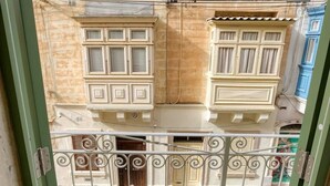 A multi-story building with balconies, a metal gate, and a window with a striped curtain. - Spectacular 5BR Townhouse located in Sliema (Tas-Sliema)