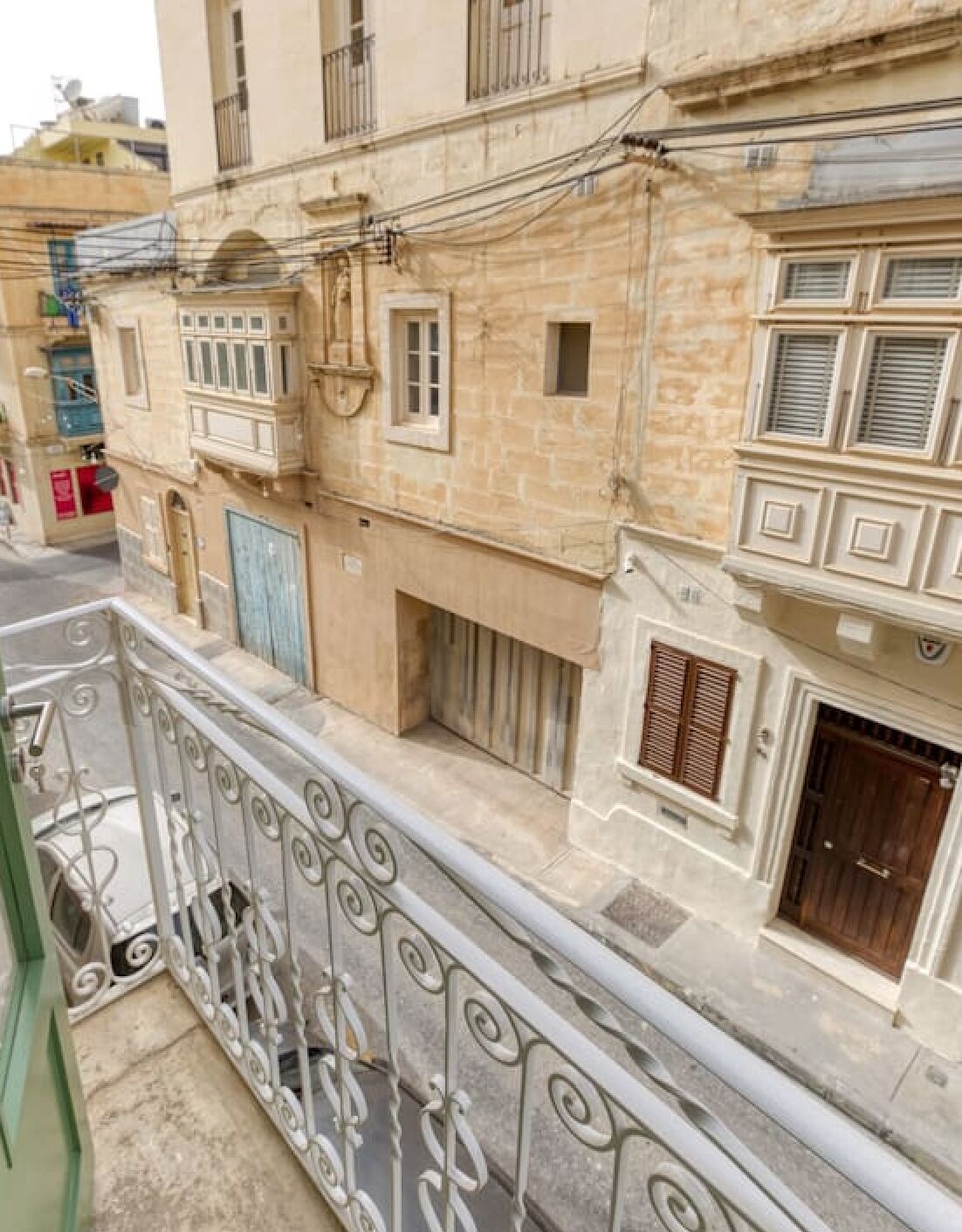 A multi-story building with stone facade, balconies with wrought iron railings, and multiple windows with shutters.