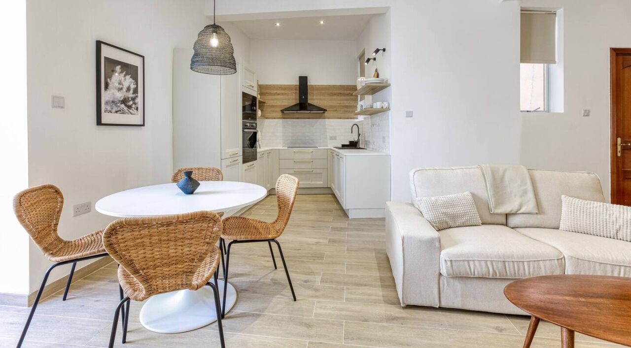 Een moderne keuken met witte kastjes, een houten aanrecht en een hangende lamp.