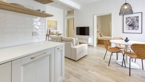 A modern kitchen with white cabinets, a wooden countertop, and a dining area with wicker chairs and a white table.