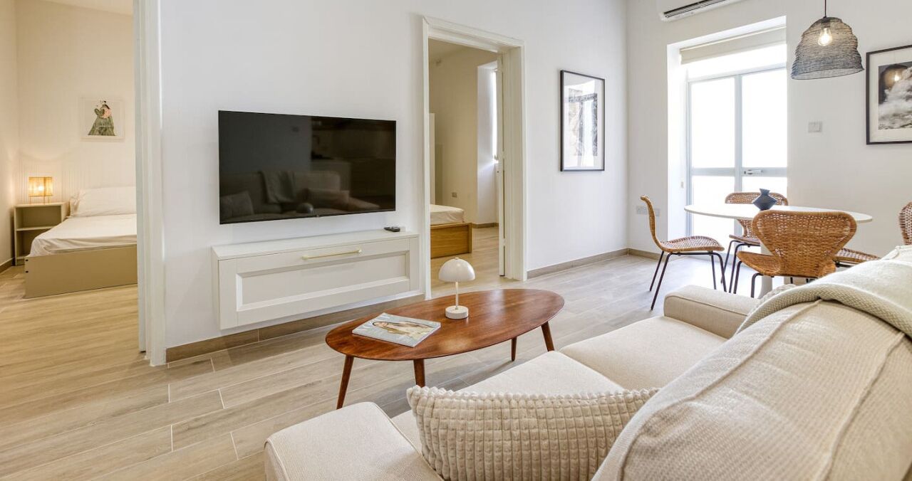 Ein modernes Wohnzimmer mit Flachbildfernseher, Couchtisch aus Holz und einer Couch.