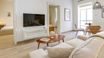 Ein modernes Wohnzimmer mit Flachbildfernseher, Couchtisch aus Holz und einer Couch.