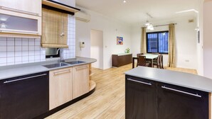 Una cucina moderna con forno integrato, lavello e zona pranzo con tavolo e sedie.
