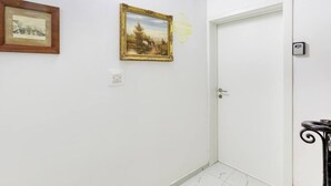 A hallway with a white door, a framed painting, and a wall-mounted light switch. - Modern Studio Apt with Private Terrace in Sliema (Tas-Sliema)