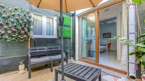 A patio area with a wooden bench, a table, and an umbrella. - Modern Studio Apt with Private Terrace in Sliema (Tas-Sliema)