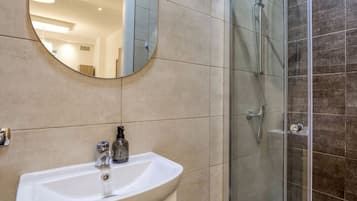 Een badkamer met een wastafel, spiegel en een douchecabine van glas.