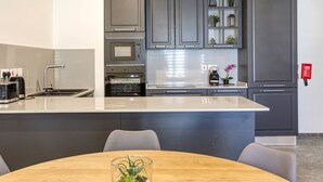 A modern kitchen with grey cabinets, a built-in oven, a coffee maker, and a sink. - Spacious 3BR home with private Balconies in Mosta (Il-Mosta)