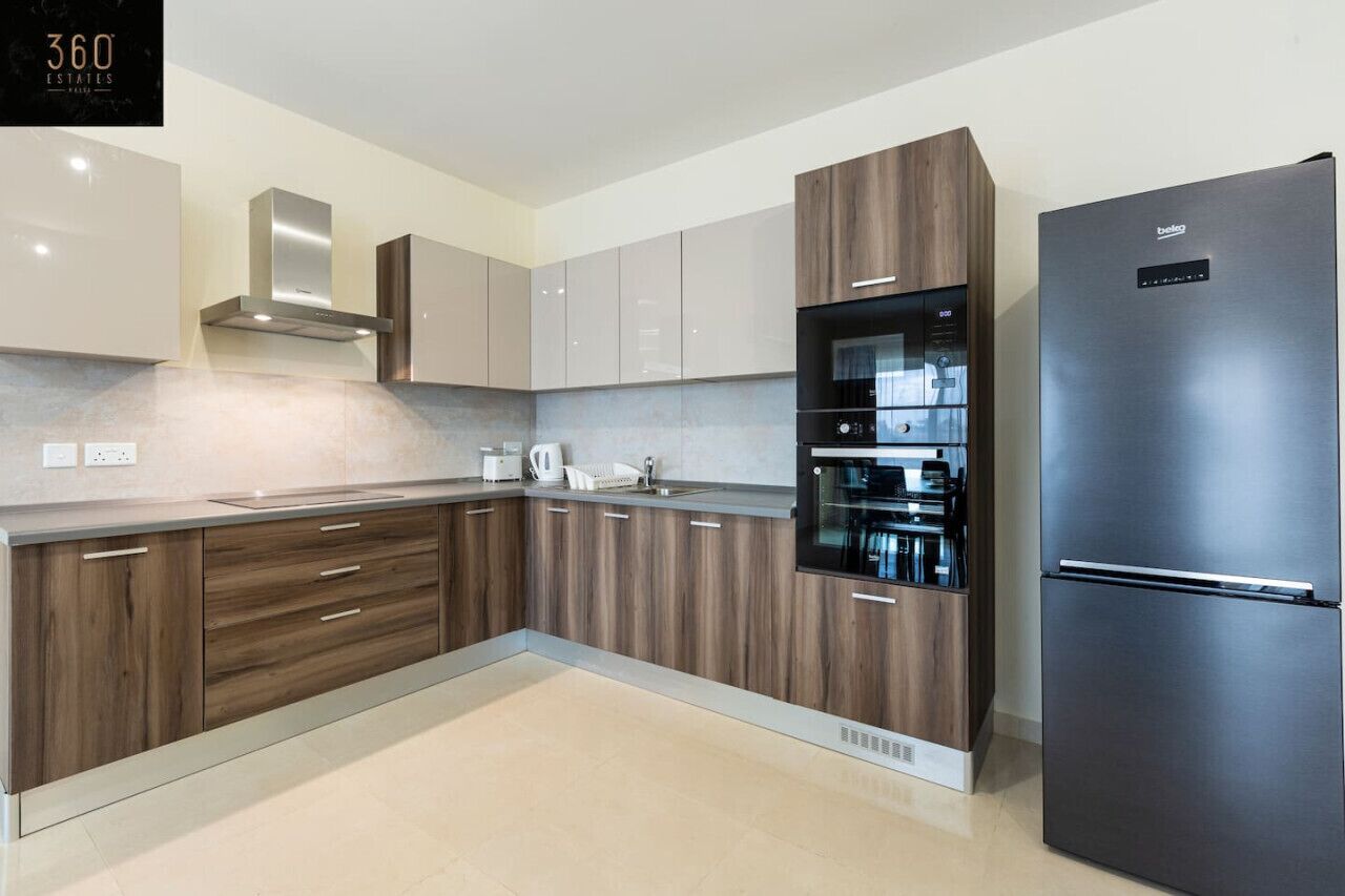 Eine moderne Küche mit Holzausstattung, einem Edelstahlkühlschrank und eingebauten Geräten.