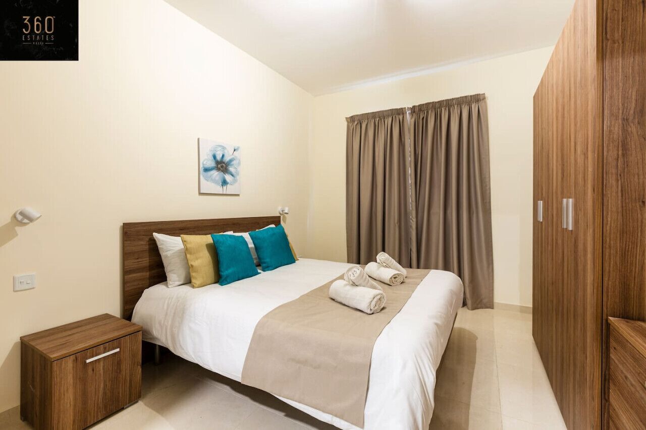 A neatly arranged hotel room with a bed, a nightstand, a wardrobe, and a painting on the wall.