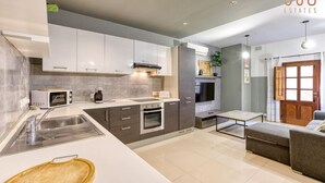 Une cuisine moderne avec des meubles blancs, un four à micro-ondes, une cuisinière et un évier. On y trouve également un coin repas avec une table et des chaises.