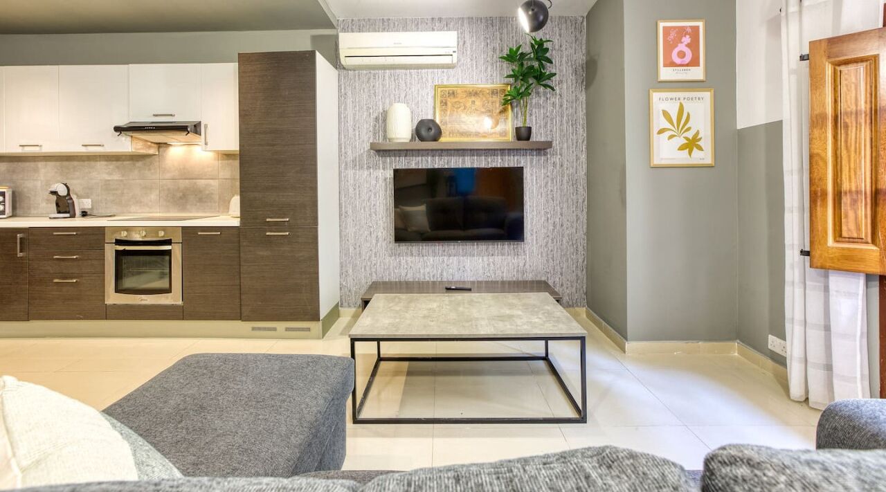 Una cocina moderna con electrodomésticos integrados, un televisor de pantalla plana y una zona de comedor minimalista.