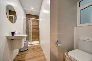 A modern bathroom with a white sink, mirror, and toilet.
