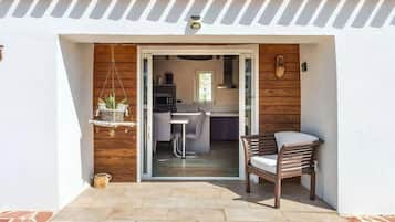 A patio with a wooden chair and a hanging plant.