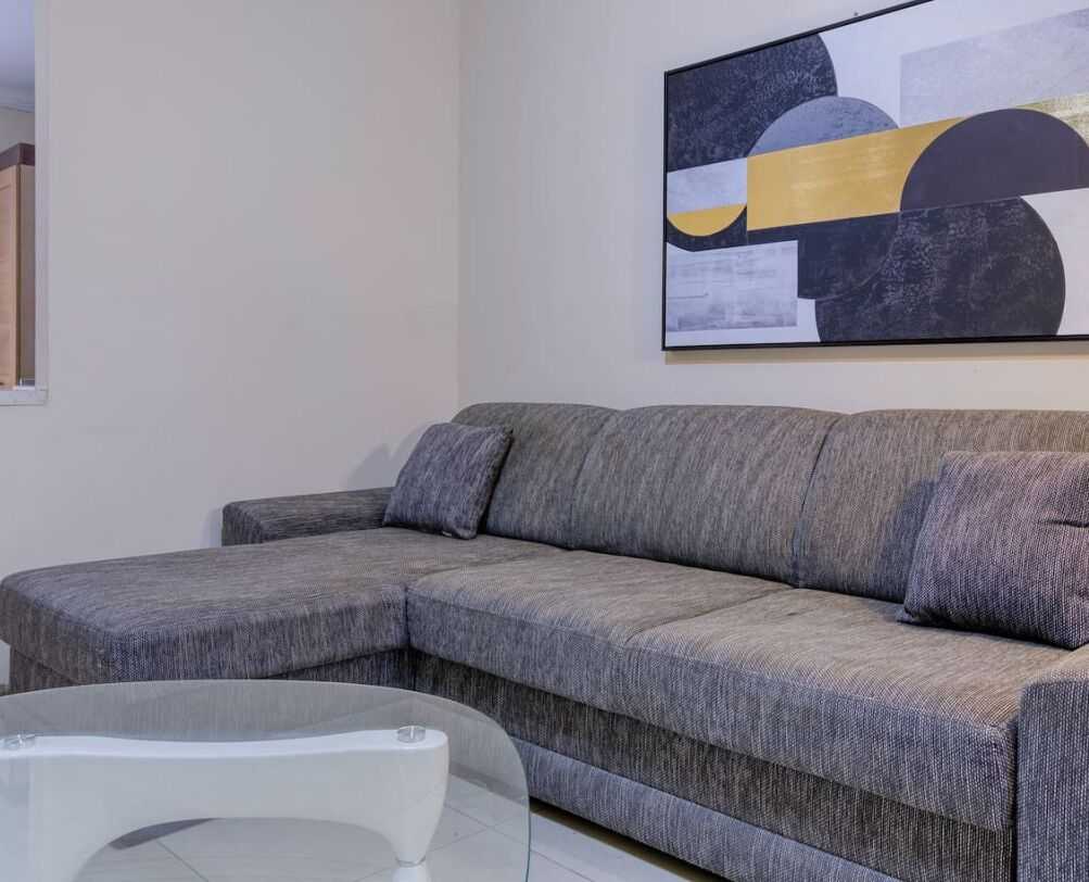 A grey sectional sofa with a glass coffee table in a modern living room.
