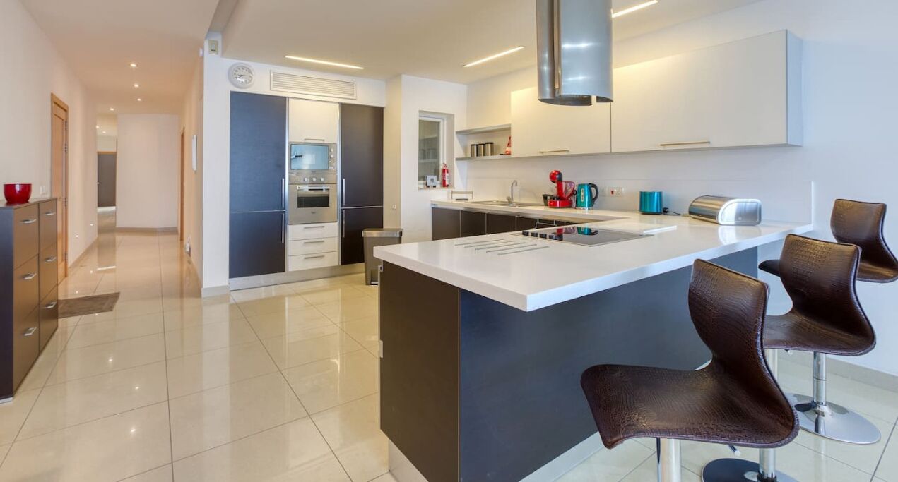 A modern kitchen with a central island, stainless steel appliances, and contemporary bar stools.