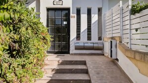 A modern building with a black door, a staircase leading to the entrance, and a white fence on the right. - Elegant & cosy 3BR home in peaceful area of Naxxar (In-Naxxar)