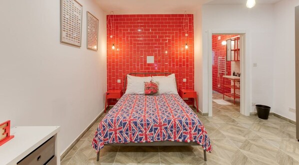 A bedroom with a red brick-patterned headboard, a patterned bedspread, and a white pillow.