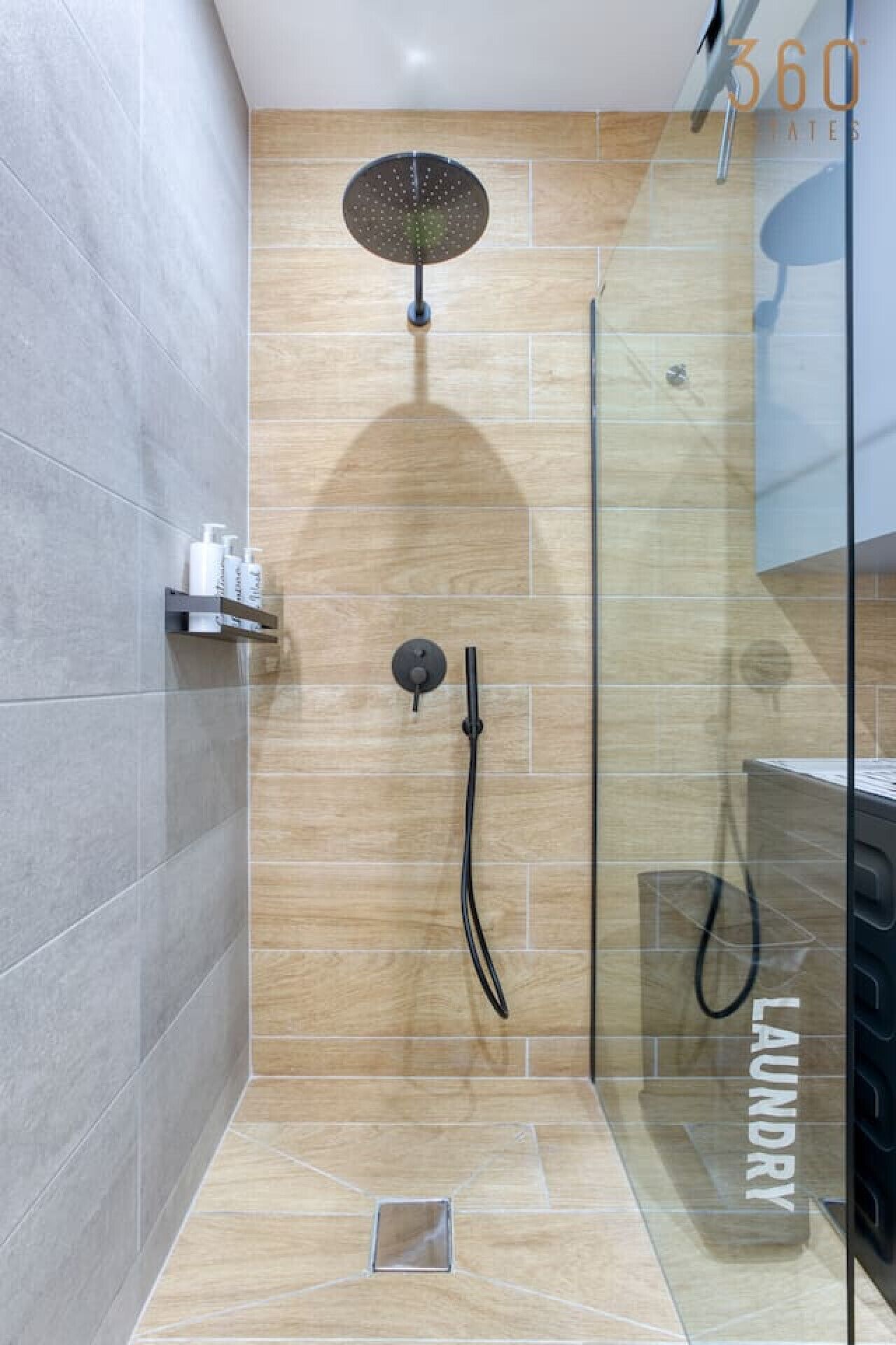 Een moderne douche ruimte met een glazen deur, een handdouche en een extra douchestraal.