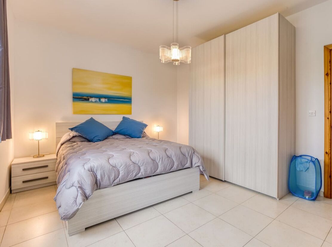 Ein Schlafzimmer mit einem Bett, Nachttischlampen, einem Gemälde und einem Kleiderschrank.