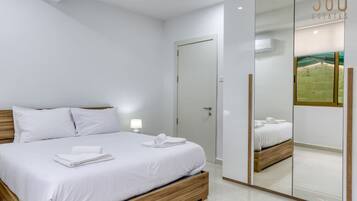 A modern bedroom with a large bed, a mirror, and a wardrobe.
