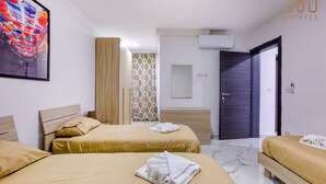 A hotel room with two beds, a large painting, an air conditioning unit, and a door leading to another room.