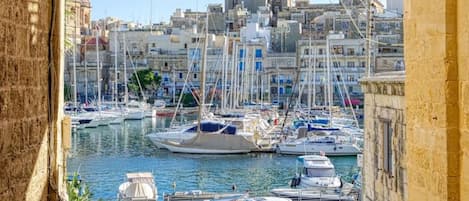 A marina with boats docked, a clear sky, and buildings in the background.