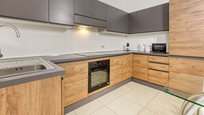 Una cocina moderna con un lavamanos de acero inoxidable, armarios de madera, horno integrado y microondas.