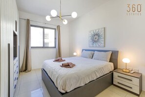 Ein modernes Schlafzimmer mit Bett, Nachttischen, einer Deckenleuchte und einem Fenster mit Vorhängen.