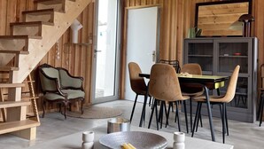 Ein modernes Interieur mit einer Holztreppe, einem Essbereich mit Stühlen und Tisch sowie einer Küchenzeile mit Herd und Schränken.
