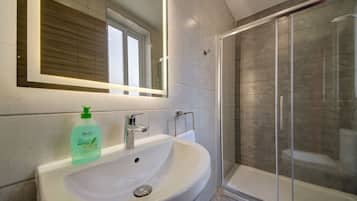 Een moderne badkamer met een witte wastafel, een spiegel en een douchecabine met glazen wanden.