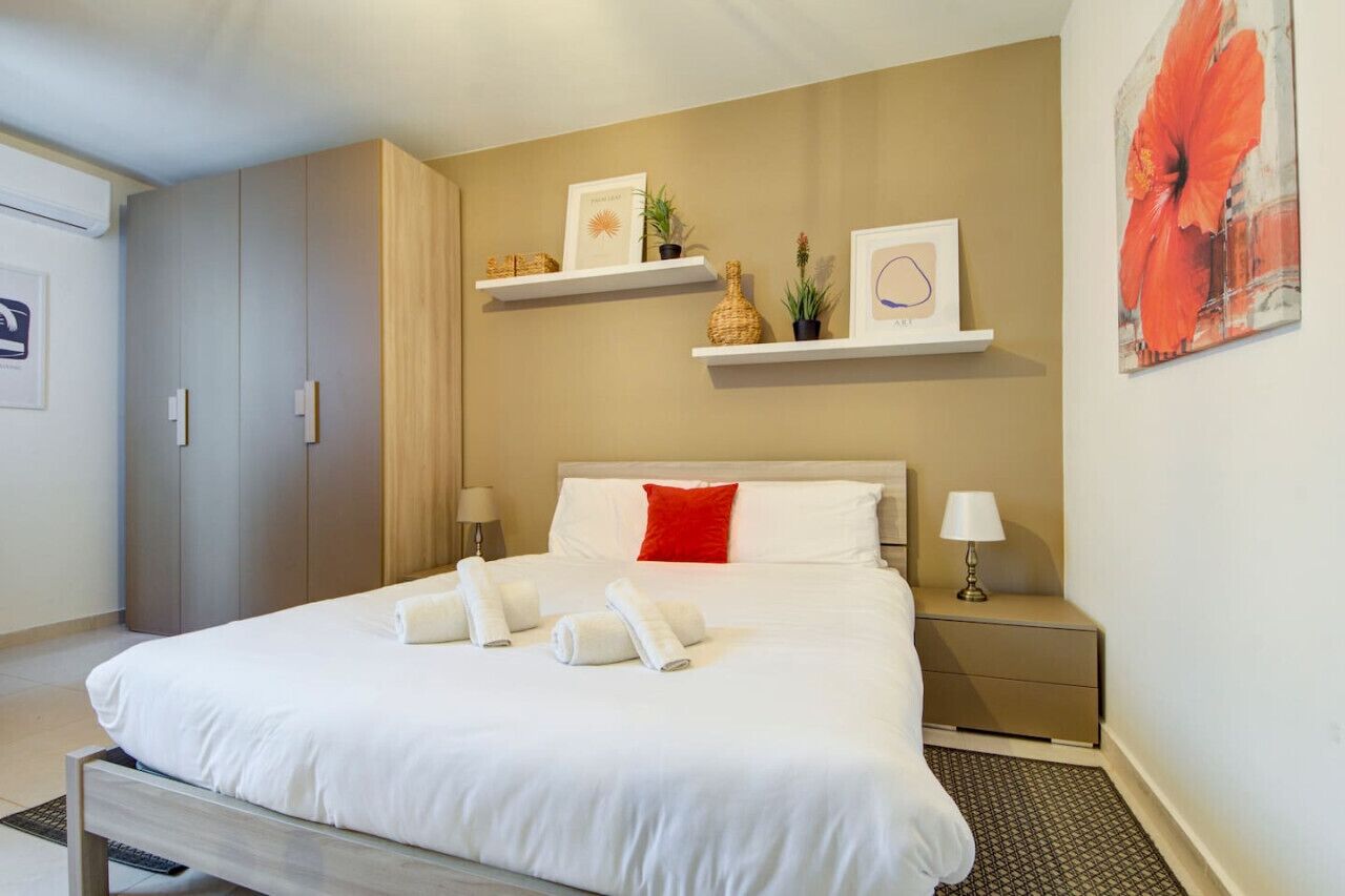 Een hotelkamer met een bed, nachtkastjes, een garderobe en wandplanken met decoratieve spullen.
