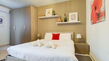 Een hotelkamer met een bed, nachtkastjes, een garderobe en wandplanken met decoratieve spullen.