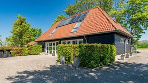 Ein Haus mit geneigtem Dach, Solaranlagen und einer gepflasterten Auffahrt.