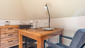Ein Essbereich mit Holztisch, zwei Stühlen, einer Lampe und einem kleinen Schrank mit Steckdose.