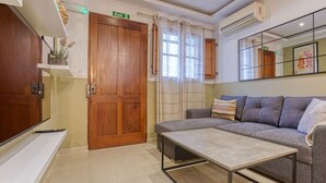 A modern living room with a sofa, a coffee table, a TV, and a wooden door. - Stylish 1BR Retreat w/ Balcony in Prime St Julian’s (St. Julian`s)