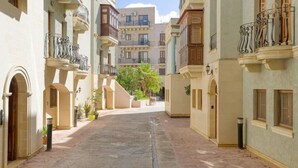 A narrow, paved courtyard with buildings on either side, featuring balconies with wrought iron railings and a palm tree in the center. - Stylish 1BR Retreat w/ Balcony in Prime St Julian’s (St. Julian`s)
