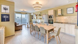 A modern kitchen with a dining area, featuring a large wooden table and chairs, a built-in oven, and a large window with a city view. - One of a kind 5BR penthouse with terrace in Pieta (Tal-Pietà)