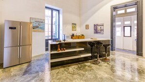 Una cocina moderna con un refrigerador de acero inoxidable, una encimera de mármol y un taburete de bar.