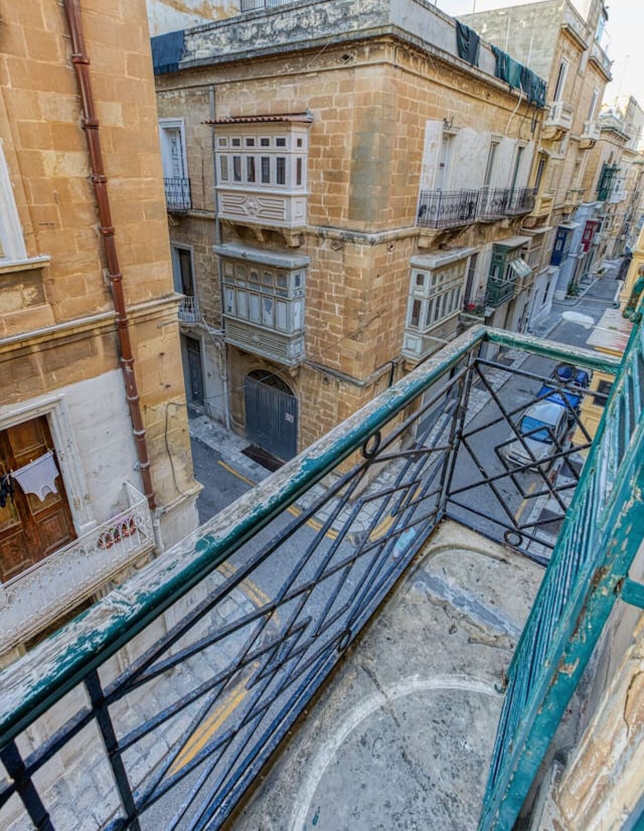 Un edificio de varios pisos con balcones, una entrada visible en la planta baja y una calle debajo.