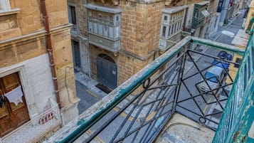 Un edificio de varios pisos con balcones, una entrada visible en la planta baja y una calle debajo.