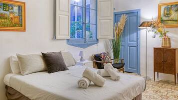 Une chambre à coucher avec un lit, des oreillers, une chaise, une armoire en bois et une fenêtre avec des volets.