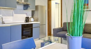 Una cocina moderna con horno empotrado, refrigerador y mesa de comedor de vidrio.
