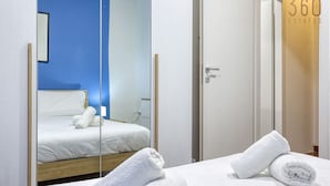 A hotel room with a bed, a mirror, and a door.