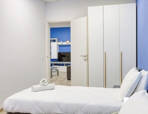 A hotel room with a bed, a wardrobe, and a bathroom visible through an open door.