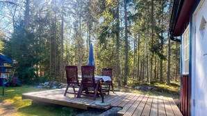 A wooden deck with a table and chairs, surrounded by a forest. - 6 Person Holiday Home in Bredaryd (Bredaryd)