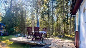 A wooden deck with a table and chairs, surrounded by a forest. - 6 Person Holiday Home in Bredaryd (Bredaryd)