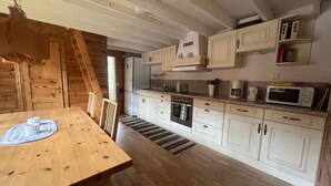 A kitchen with wooden cabinets, a stove, a microwave, and a dining table with chairs. - 6 Person Holiday Home in Bredaryd (Bredaryd)