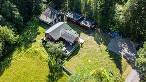An aerial view of a forested area with three buildings, likely cabins or houses, surrounded by dense trees. - 6 Person Holiday Home in Bredaryd (Bredaryd)