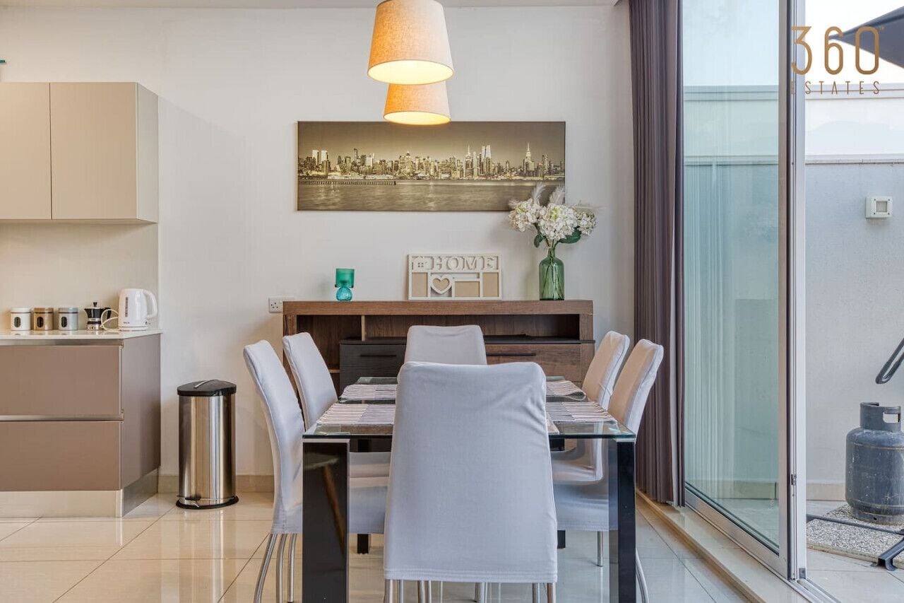 Una cocina moderna con zona de comedor, un cuadro de paisaje urbano y vistas al exterior.