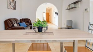A modern living room with a dining table, a sofa, and a potted plant.